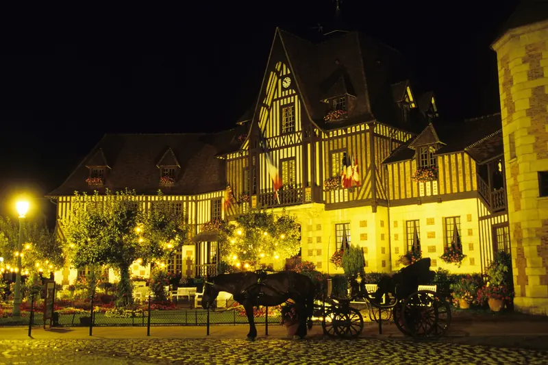 Façade à colombages illuminée à Deauville la nuit, avec une calèche